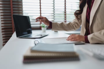 Mujer de negocios en su escritorio revisando documentos junto a una computadora portátil