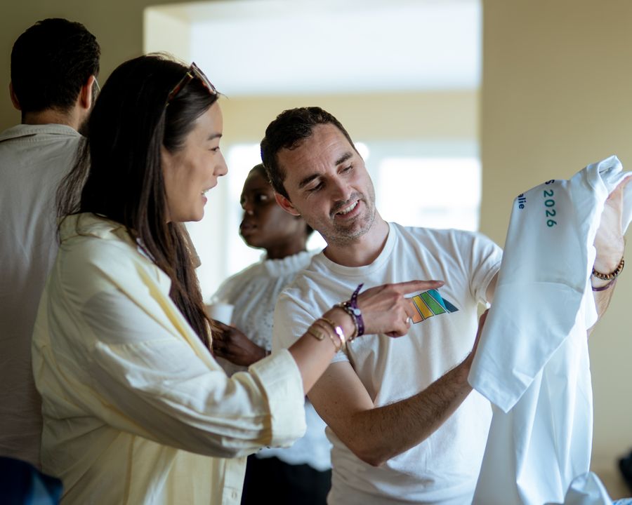 Integrantes del equipo de Orbiss miran sonrientes una camiseta durante un evento de equipo