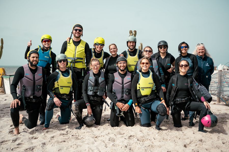 El equipo de Orbiss con trajes de neopreno y chalecos en la playa antes de una actividad acuática