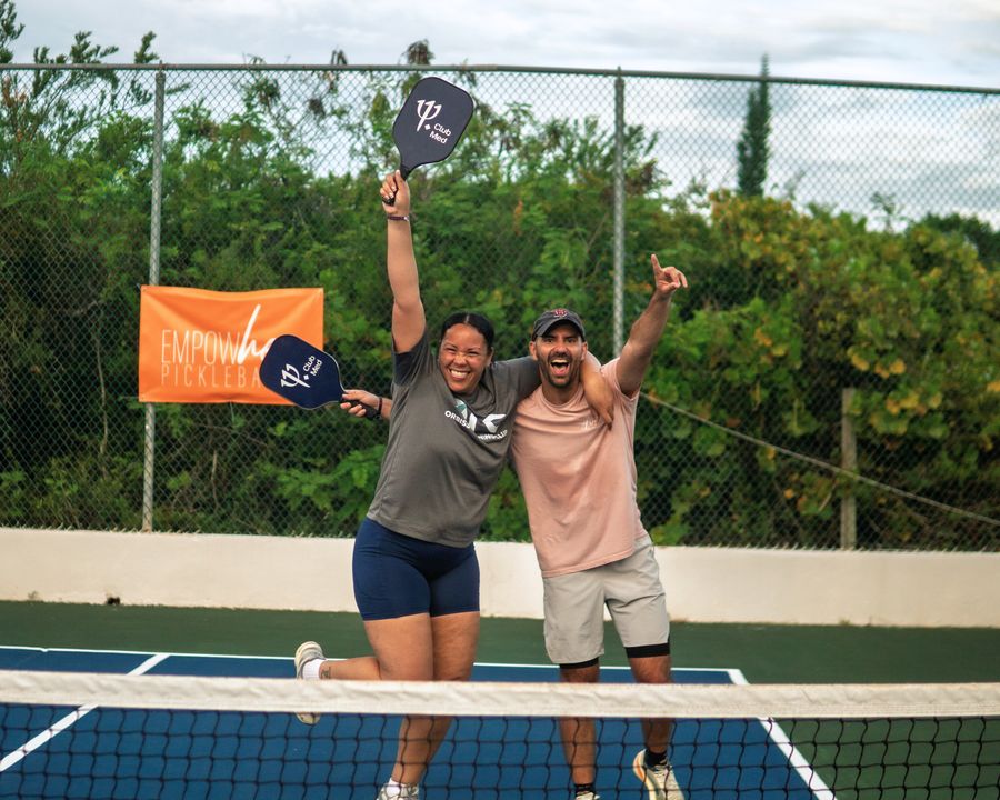 Dos integrantes del equipo de Orbiss celebran con sus palas en una cancha de pickleball