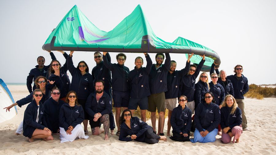 El equipo de Orbiss sostiene una cometa de kitesurf sobre sus cabezas en la playa