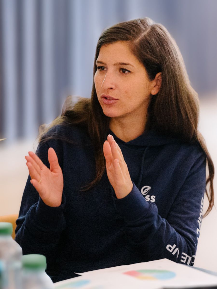 Orbiss team member in an Orbiss hoodie speaking at a meeting table