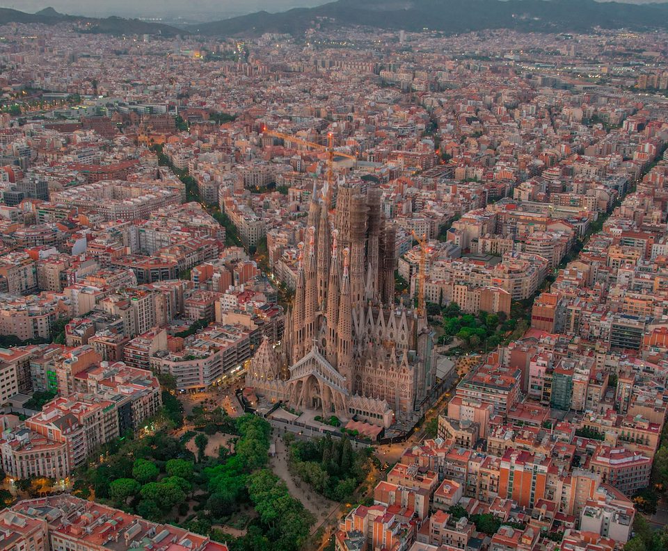 Aerial view of Barcelona at dusk, with the Sagrada Família rising above the Eixample district