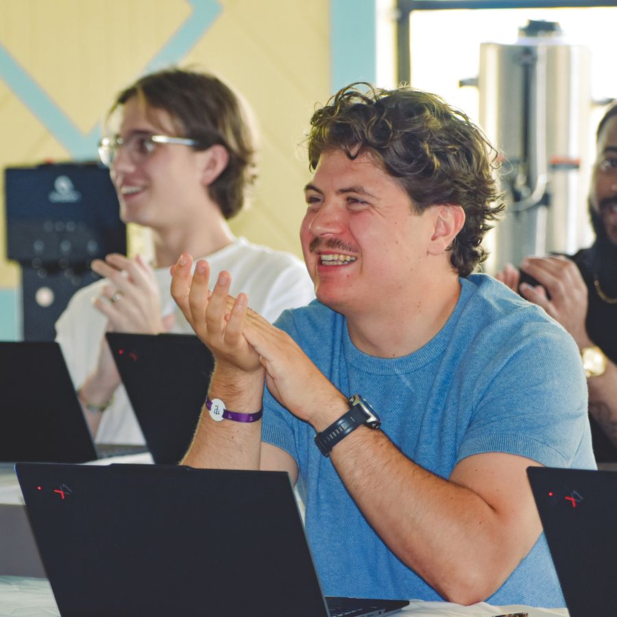 Integrantes del equipo de Orbiss aplaudiendo frente a sus computadoras portátiles durante una sesión de equipo
